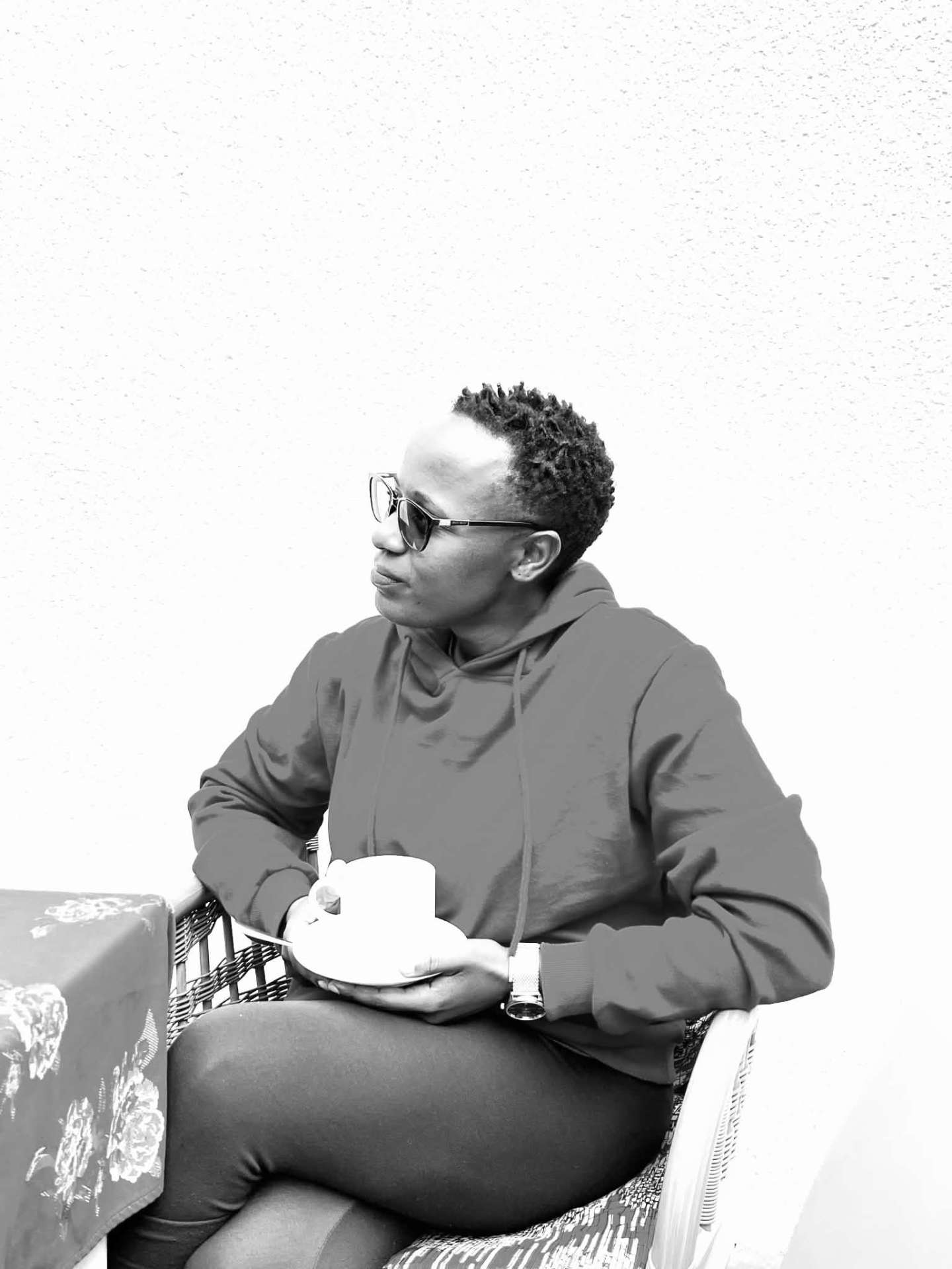 A woman in a grey hoodie sitting quietly with a cup of coffee
